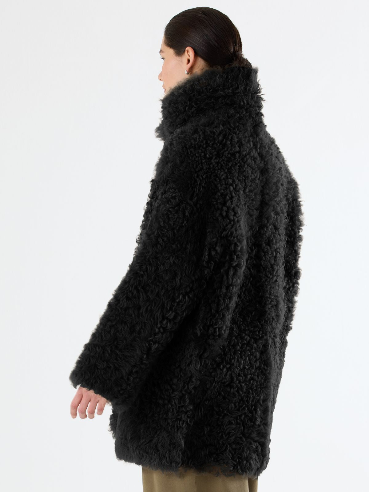 back view of woman wearing Black Relaxed Fit Curly Shearling Coat by Gushlow & Cole over green trousers