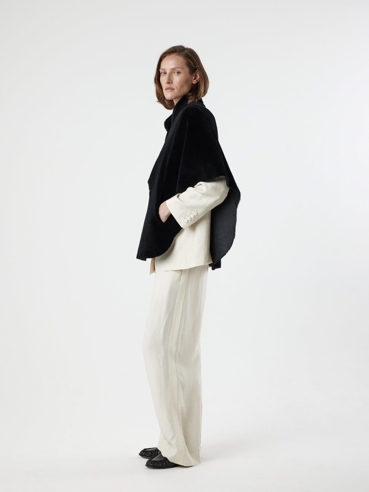 side view of woman wearing Black Shearling Cape Jacket in merino by gushlow & cole on white background