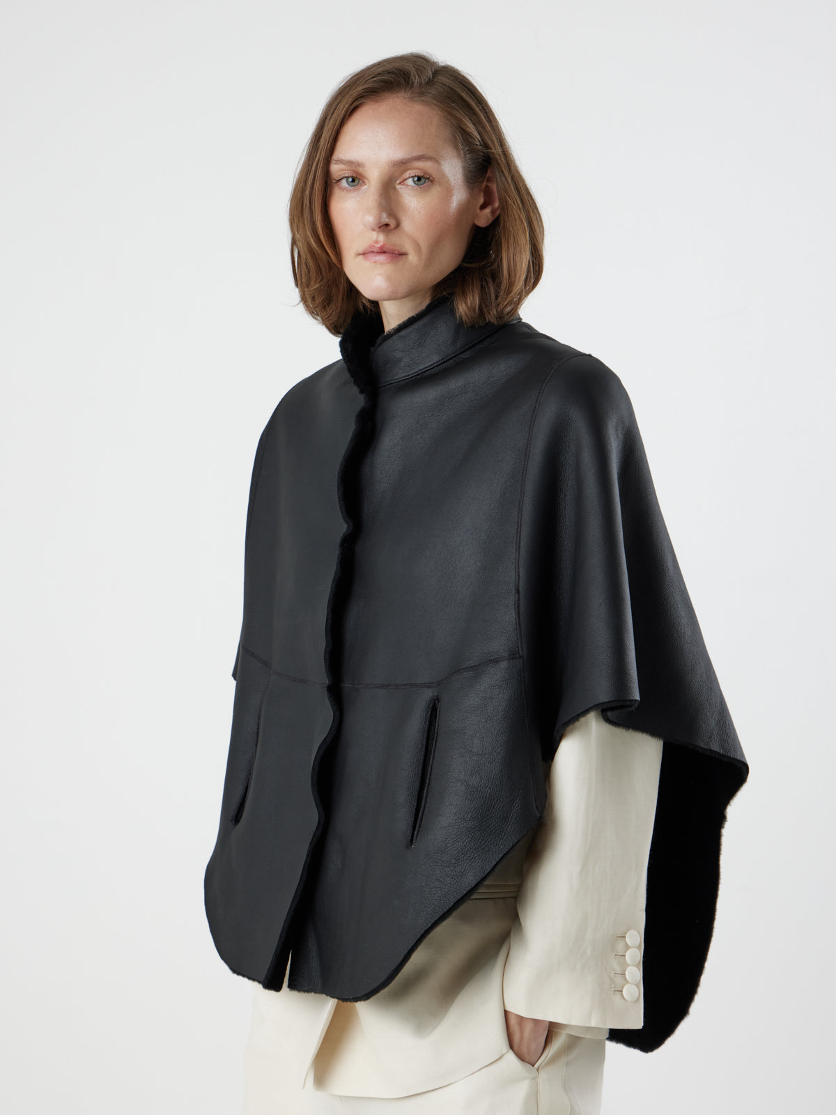 woman wearing reversed Black Shearling Cape Jacket in merino by gushlow & cole on white background