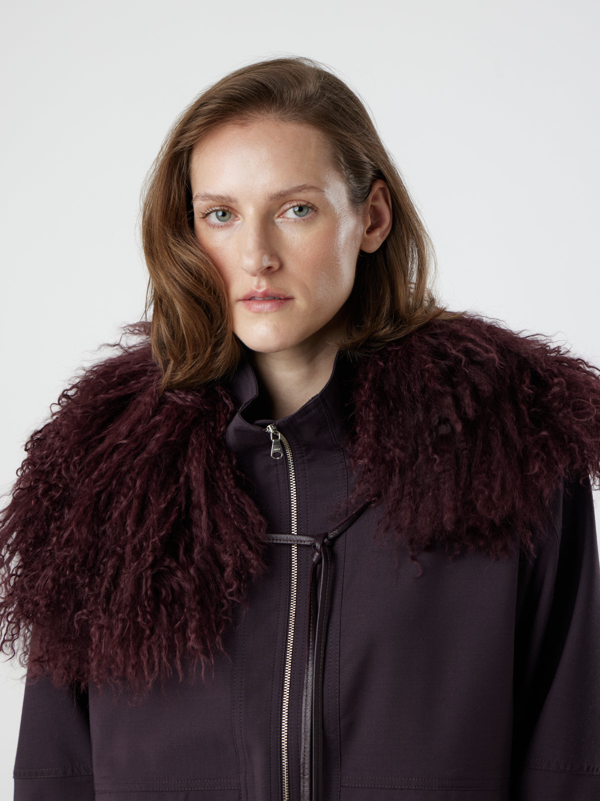 Woman wearing burgundy Mongolian Shearling Collar Scarf tied at front by gushlow & cole on white background