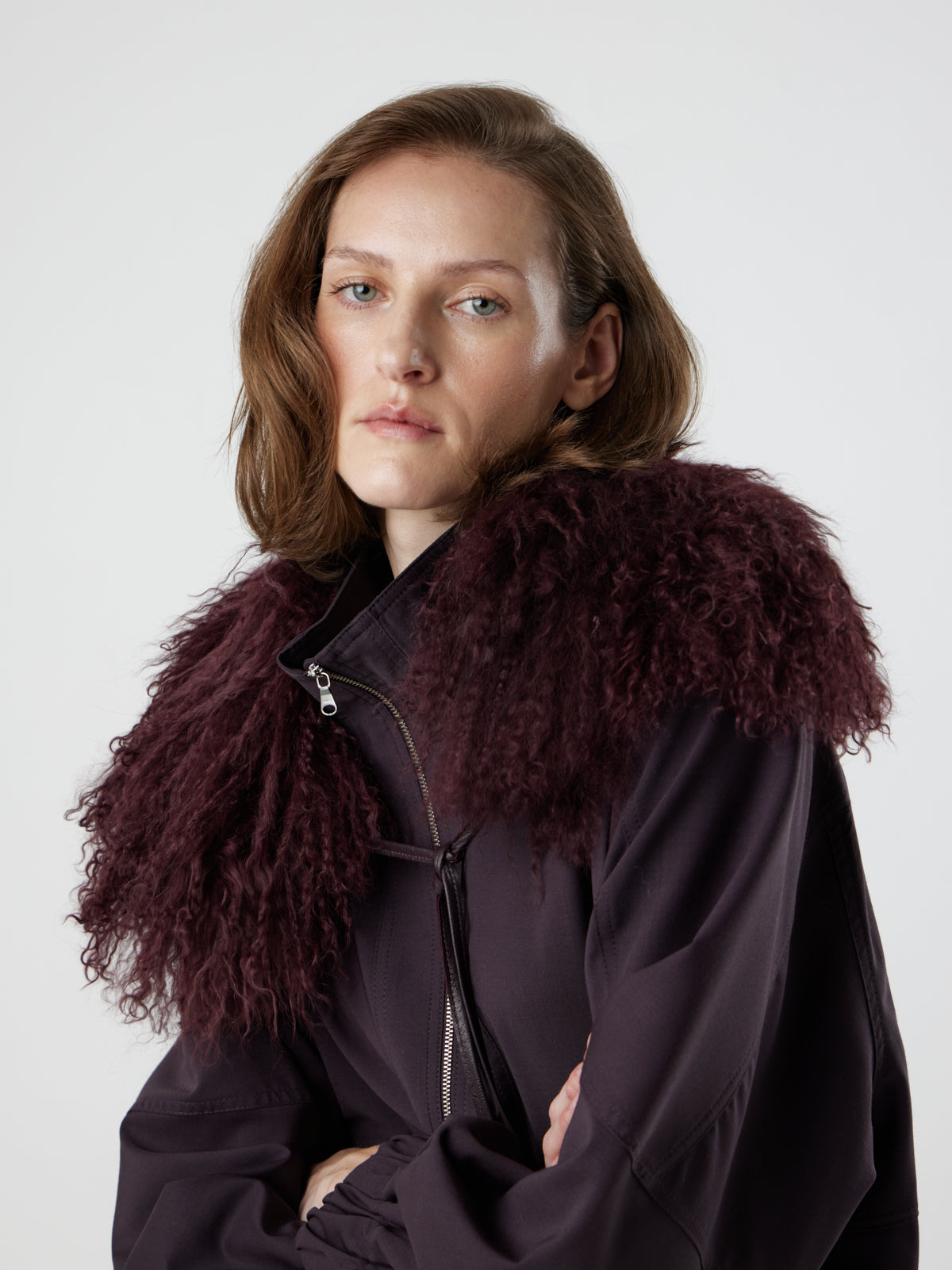 Woman wearing burgundy Mongolian Shearling Collar Scarf with arms crossed by gushlow & cole on white background
