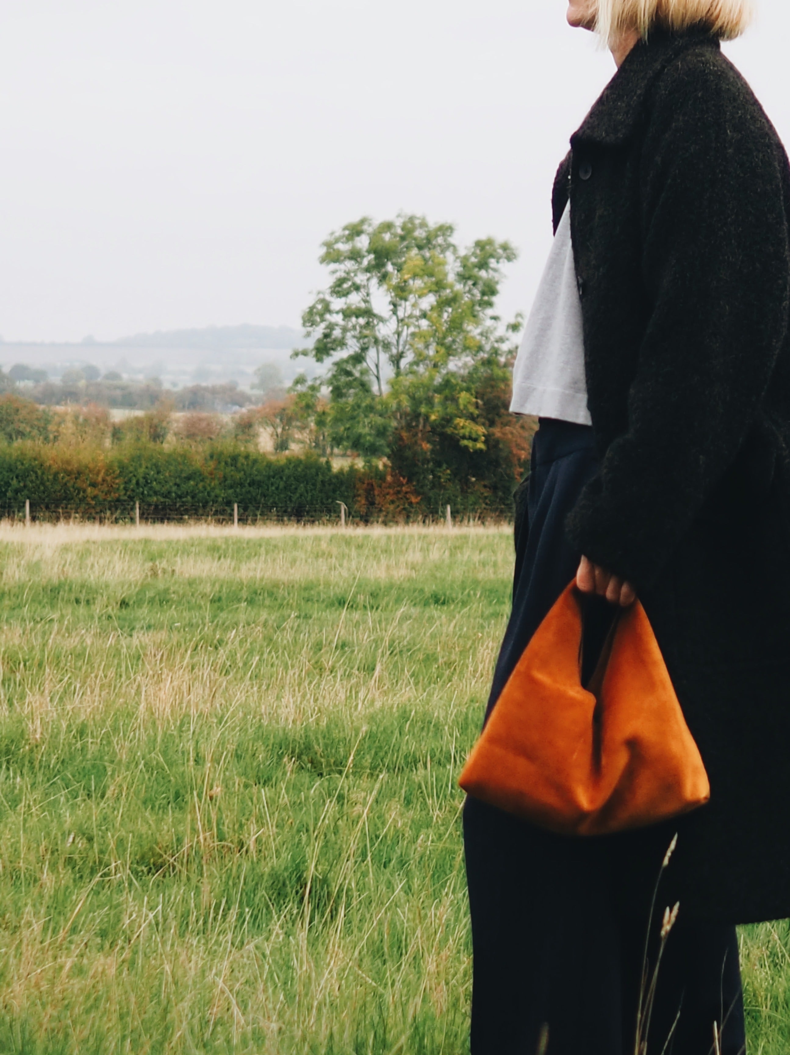 woman walking through fields with Clara Small Tan Suede Shoulder Bag by gushlow & cole