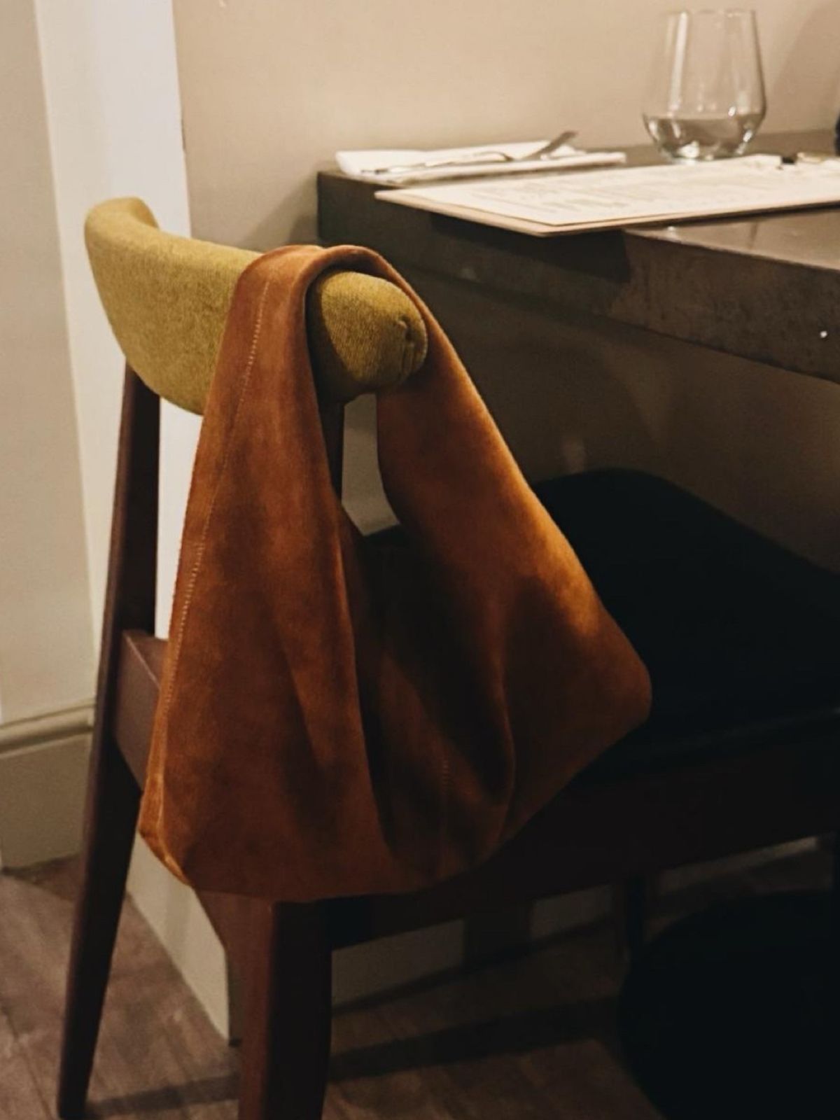 Clara Small Tan Suede Shoulder Bag by gushlow & cole hanging on the back of a chair