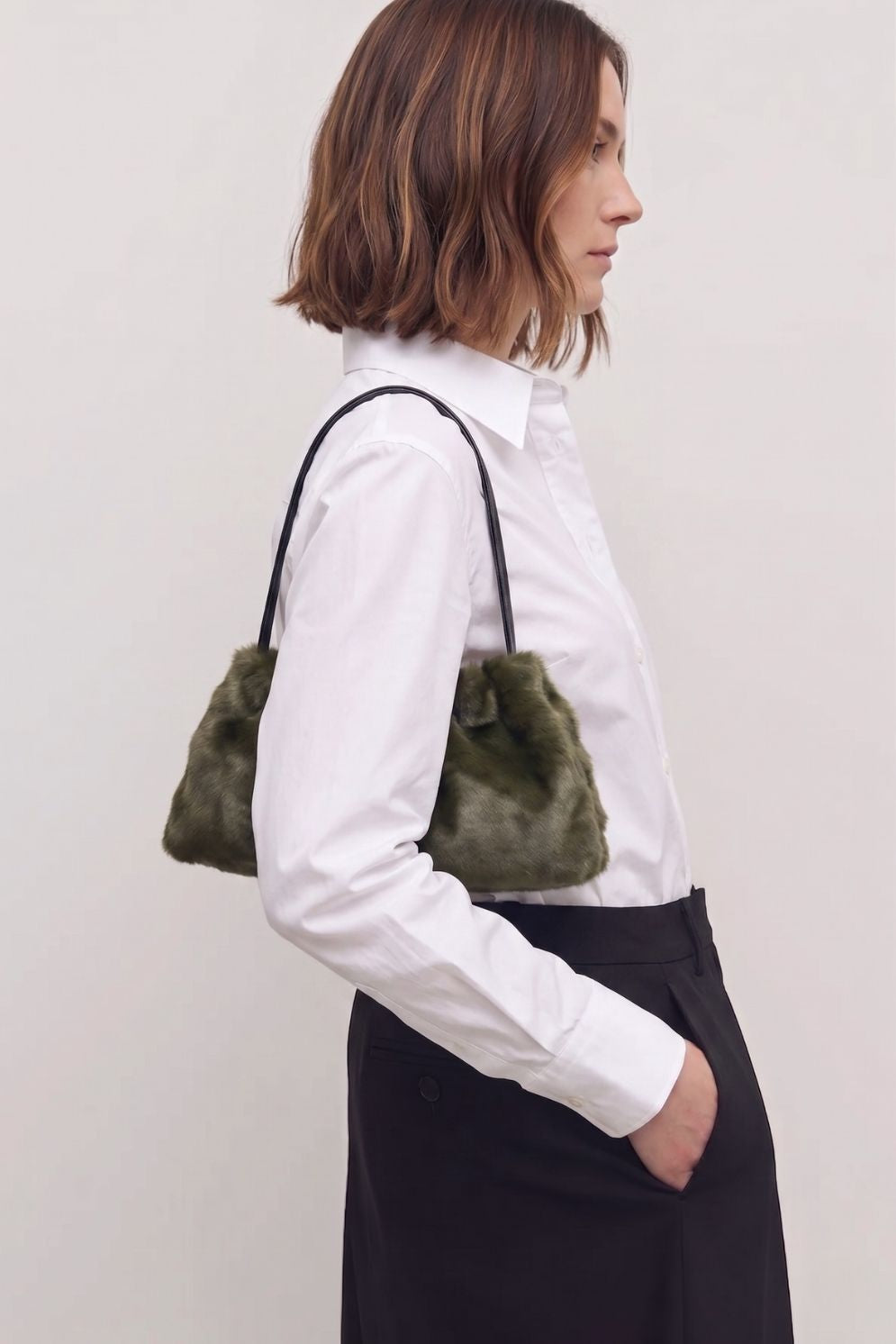 woman in white shite wearing ghia small green shoulder bag made in calfskin on white background by gushlow & cole
