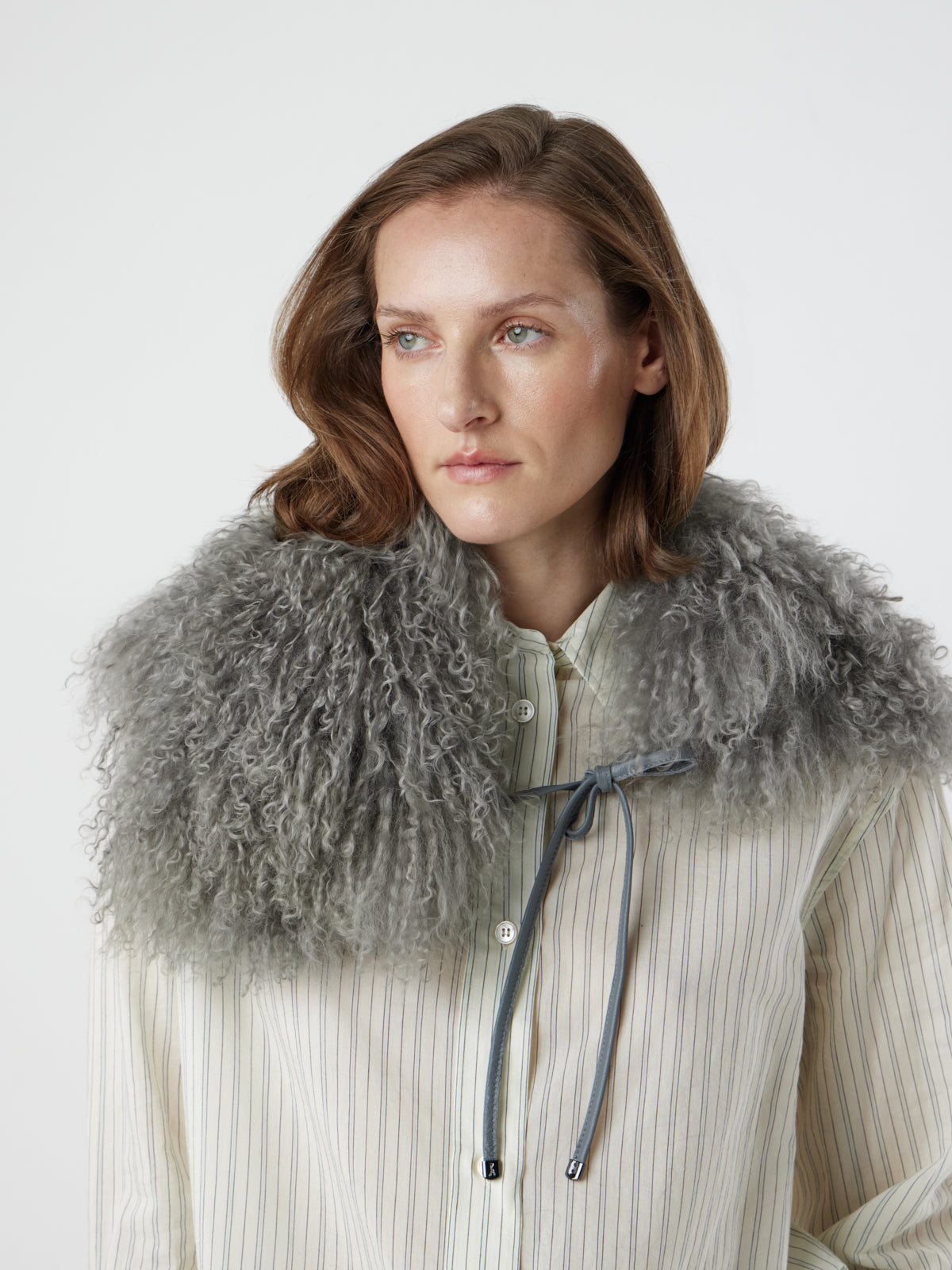 Woman wearing grey Mongolian Shearling Collar Scarf over stripe shirt by gushlow & cole