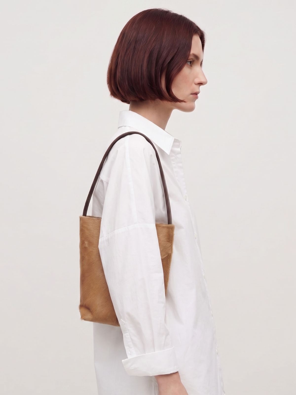 woman wearing maye small camel bucket tote bag by gushlow & cole with white shirt