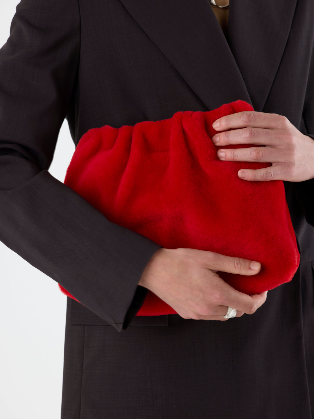 woman holding Red Merino Soft Shearling Clutch by Gushlow & Cole over brown suit
