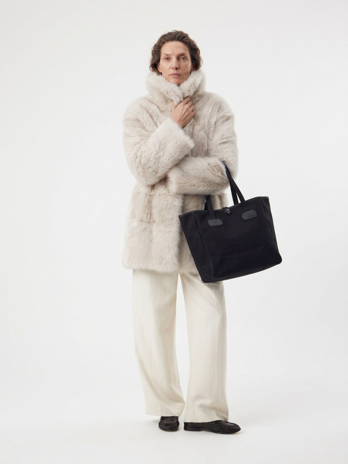 woman wearing relaxed fit white toscana shearling coat holding black brady bag by gushlow & cole