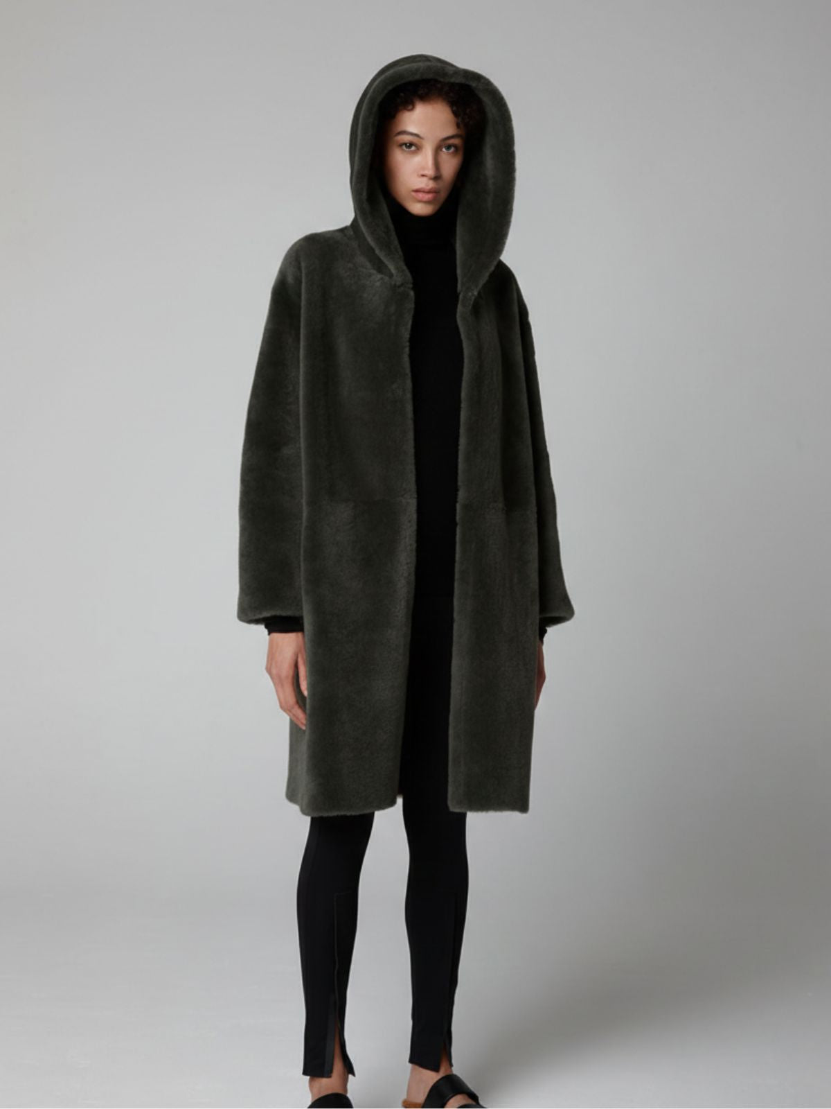 women wearing Storm Green Hooded Shearling Coat by Gushlow & Cole on grey background with hood up