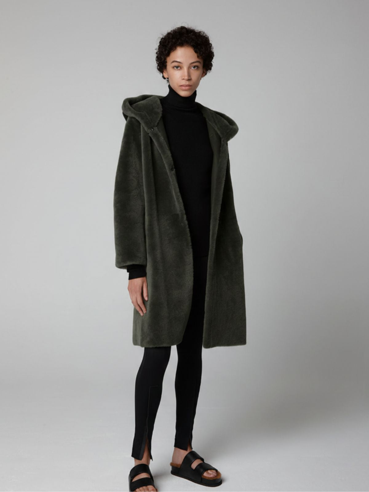 women wearing Storm Green Hooded Shearling Coat by Gushlow & Cole on grey background with hood down