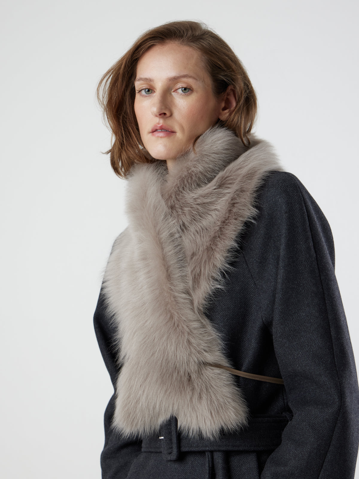 side view of woman wearing taupe Shearling Shawl Scarf with nappa leather ties, styled crossed over, by gushlow & cole on white background