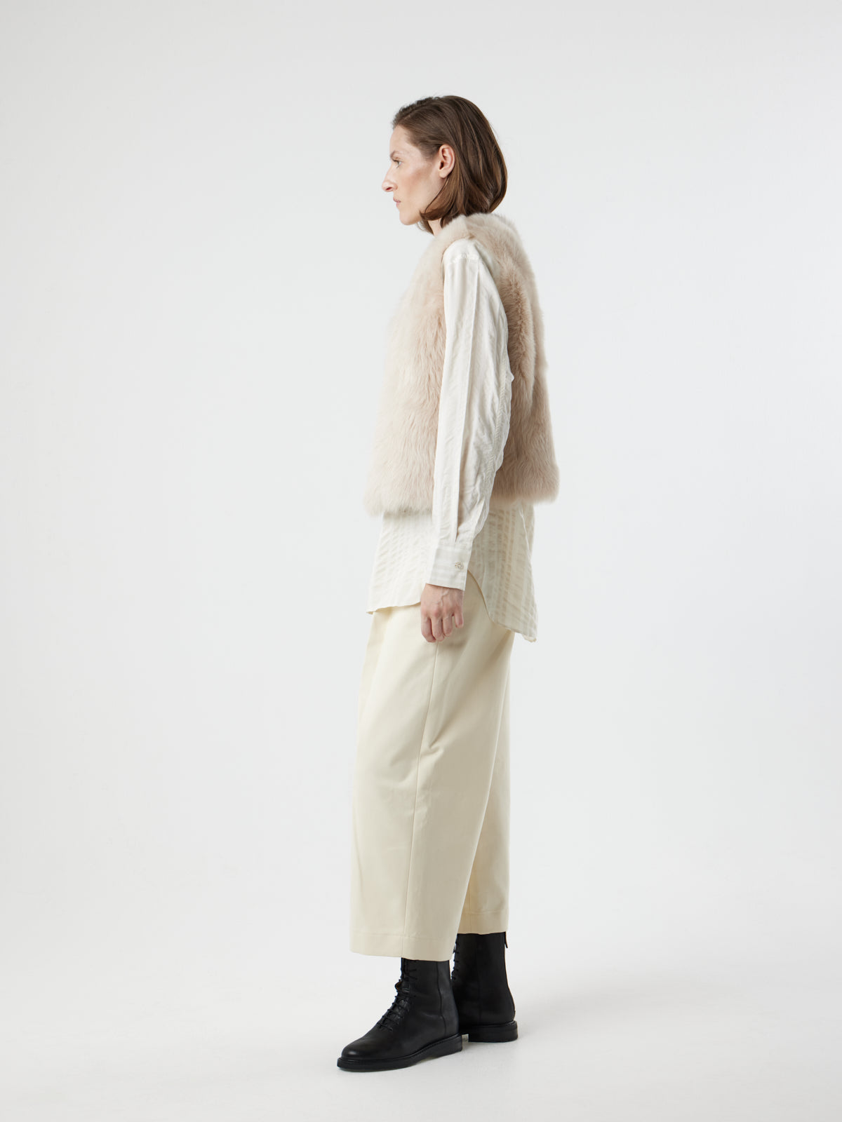 side view of woman wearing Two Button Cream Shearling Vest by gushlow & cole on white background