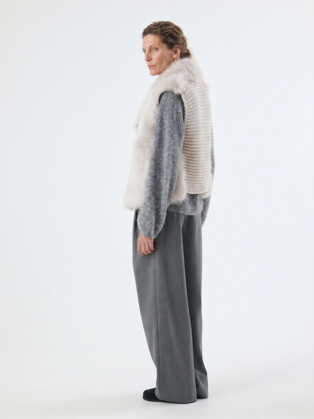back view of woman wearing white shearling and hand knit gilet by gushlow & cole