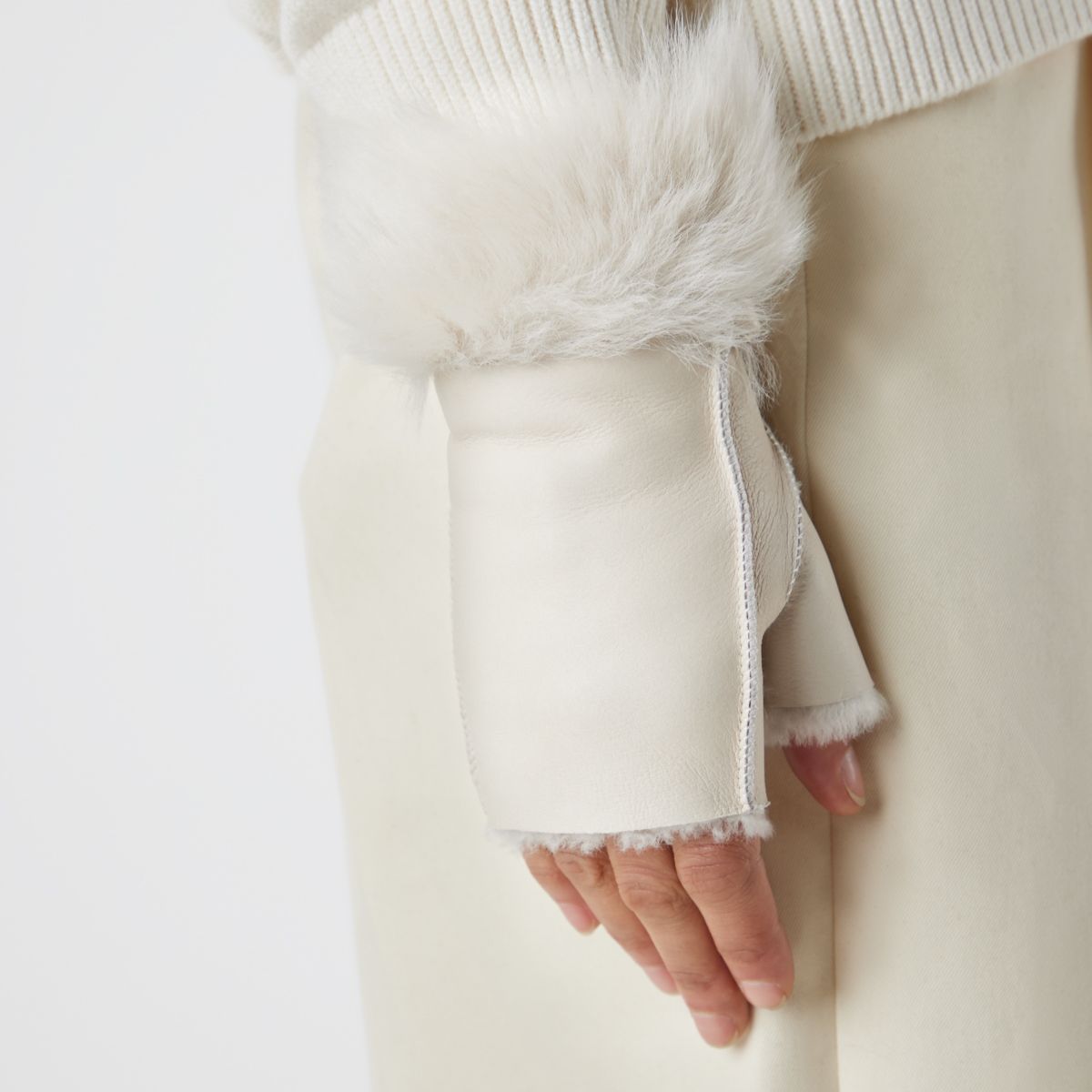 cream fingerless shearling mittens on womans hand by gushlow & cole