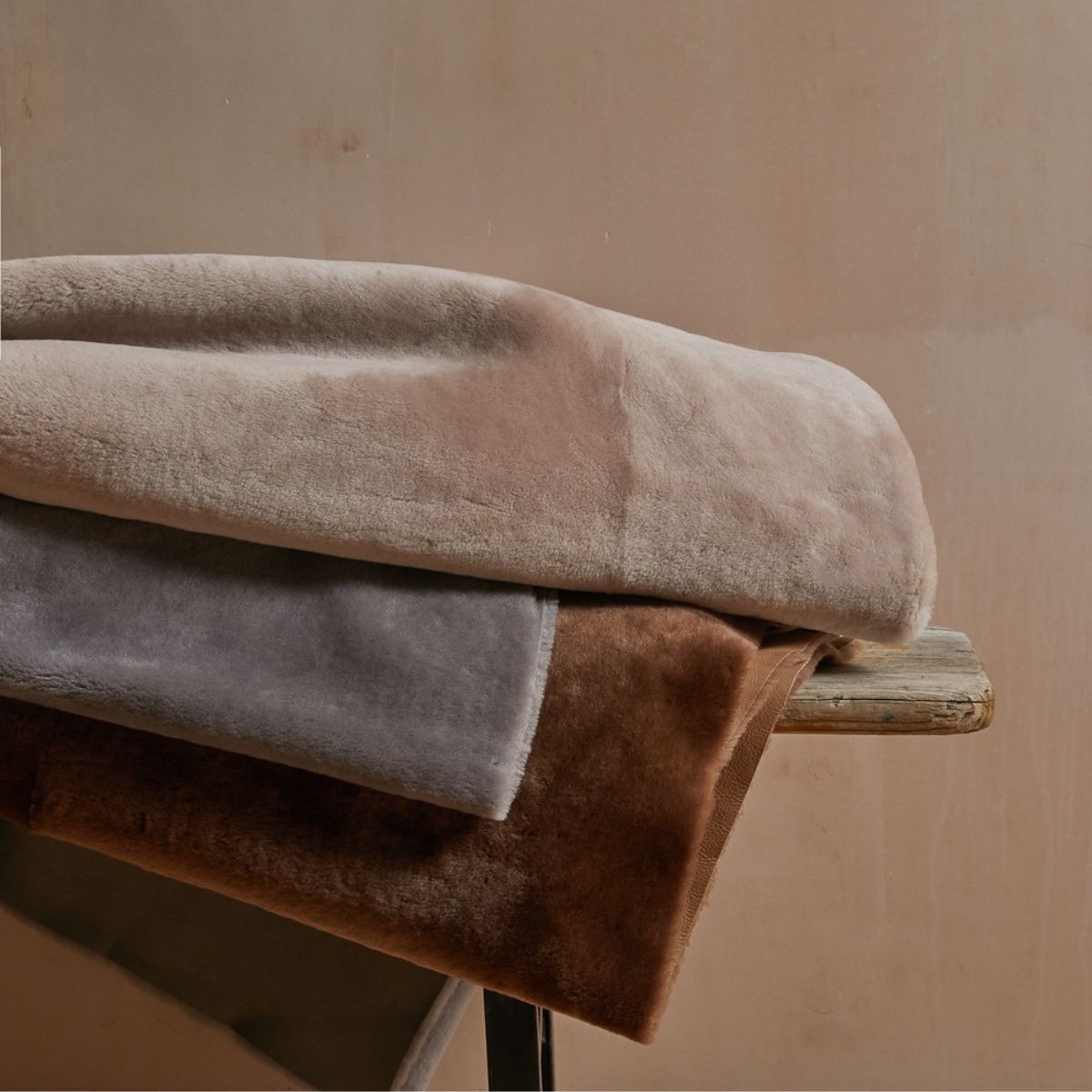 merino shearling throws by gushlow & cole on wooden bench