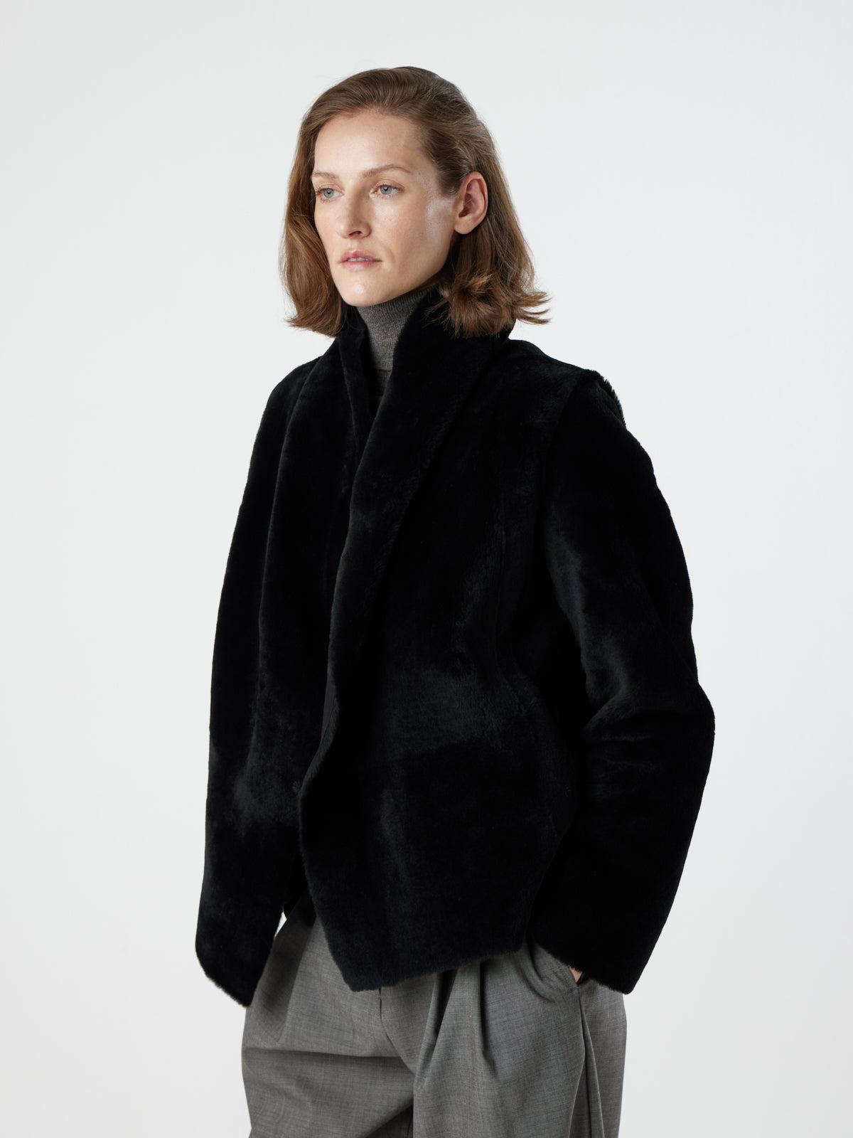 woman wearing reversed Black Blanket Shawl Shearling Jacket by gushlow & cole on white background with hands in pockets