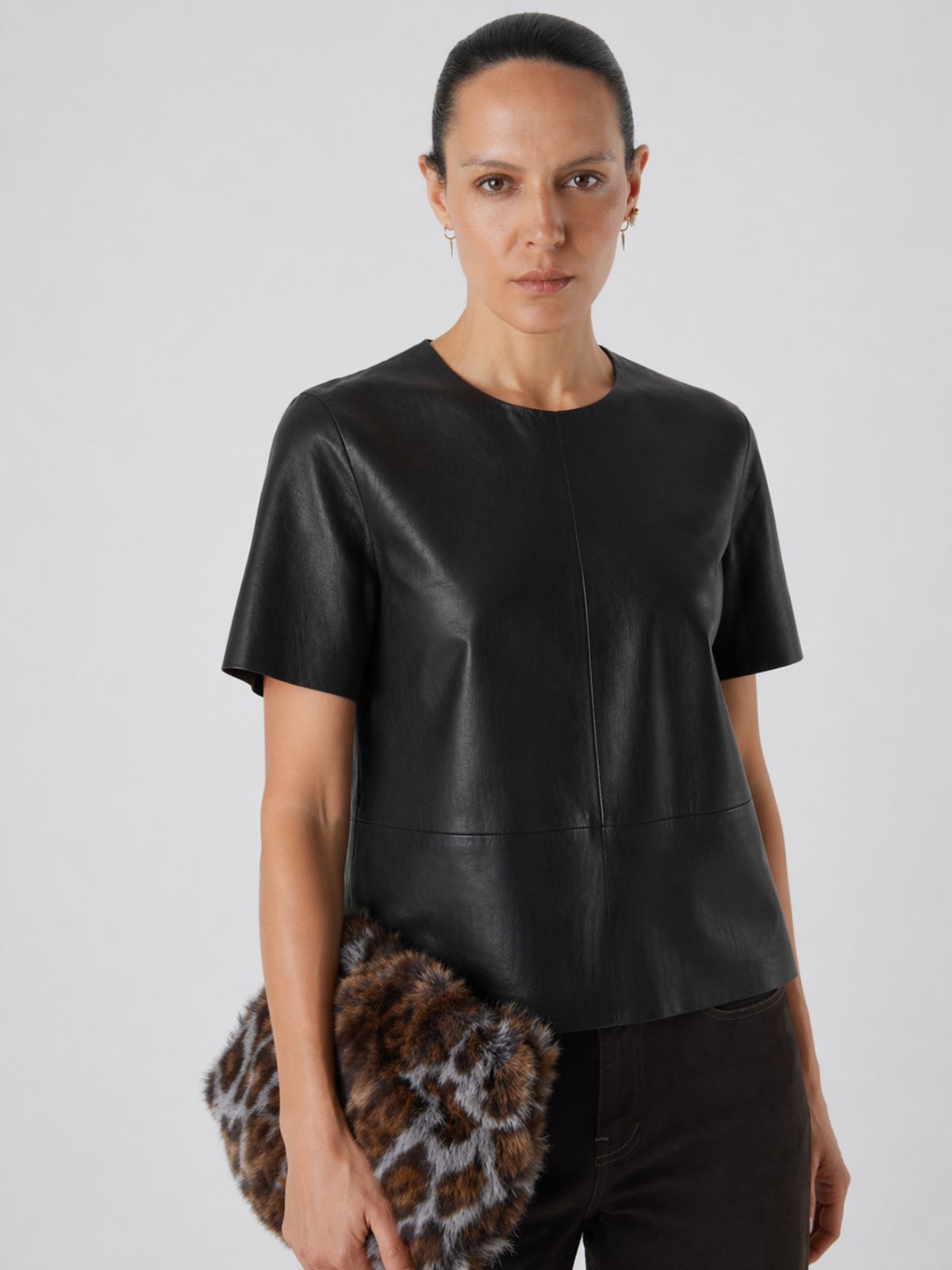 woman wearing black leather t shirt top holding shearling bag on white background by gushlow & cole