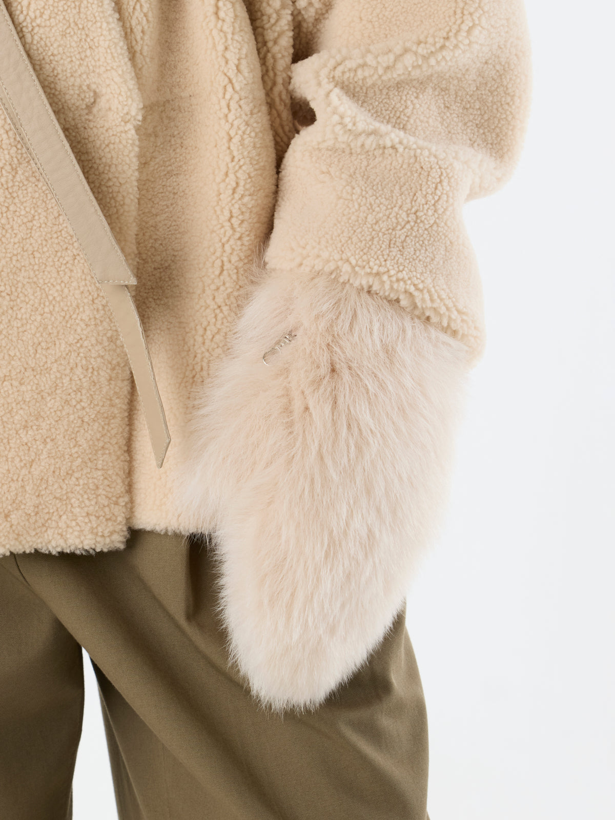 womens hand wearing Cream Touchscreen Shearling Mittens and cream Collarless Shearling Wrap Jacket by Gushlow & Cole
