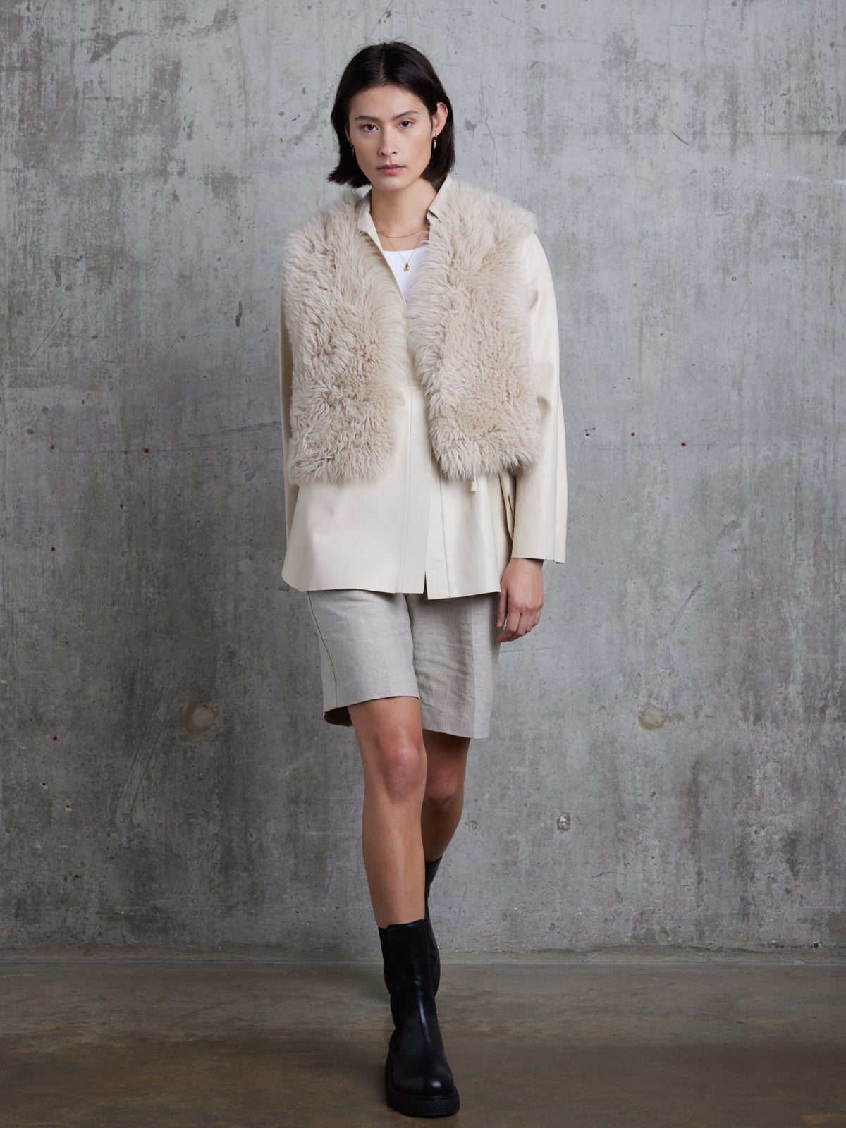 woman wearing  slip-on cream Two Button Shearling Vest by gushlow and cole on grey background walking