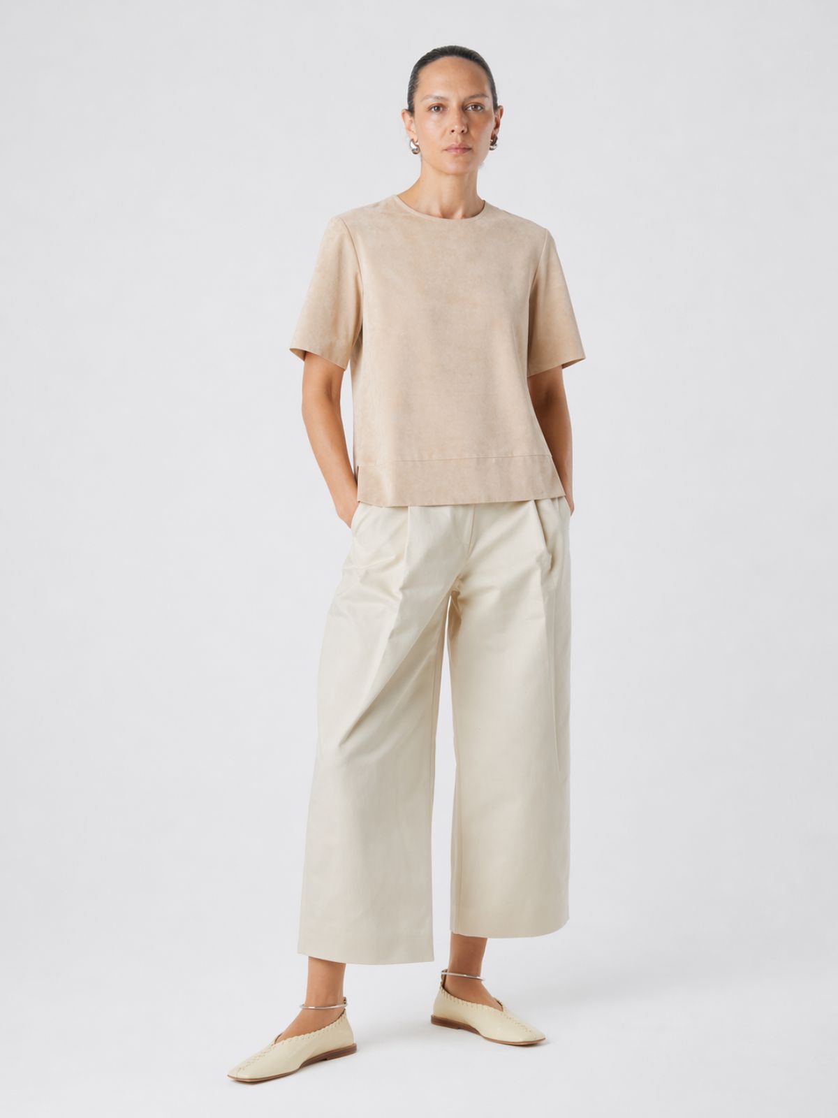 woman wearing cream suede t shirt top and cream leather culottes on white background by gushlow & cole
