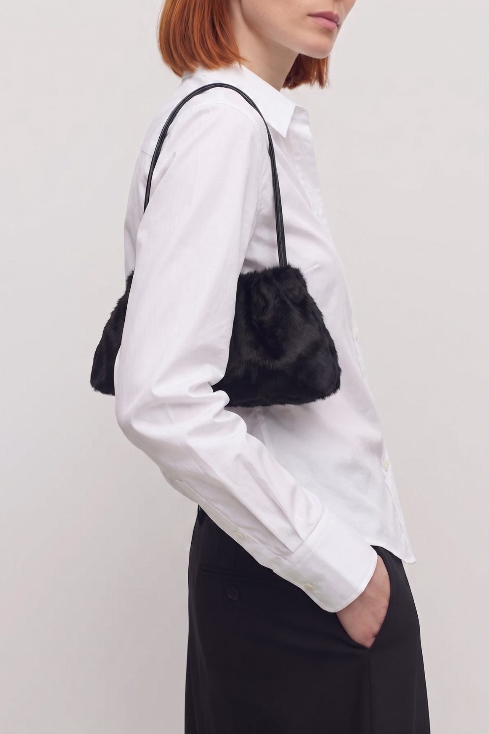 woman wearing ghia small black shoulder bag made in calfskin on white background by gushlow & cole