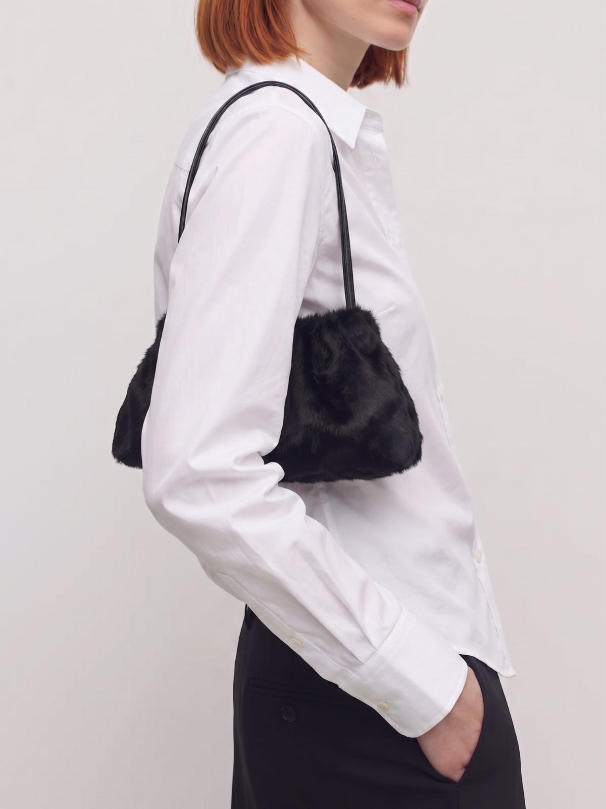 woman wearing ghia small black shoulder bag made in calfskin on white background by gushlow & cole