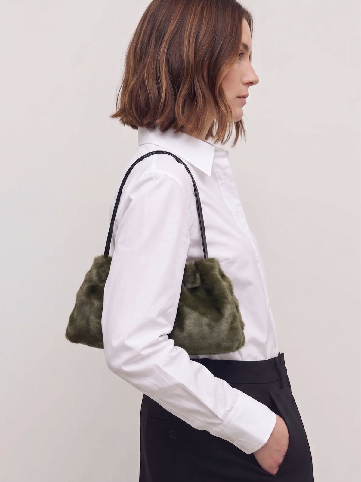 woman in white shite wearing ghia small green shoulder bag made in calfskin on white background by gushlow & cole