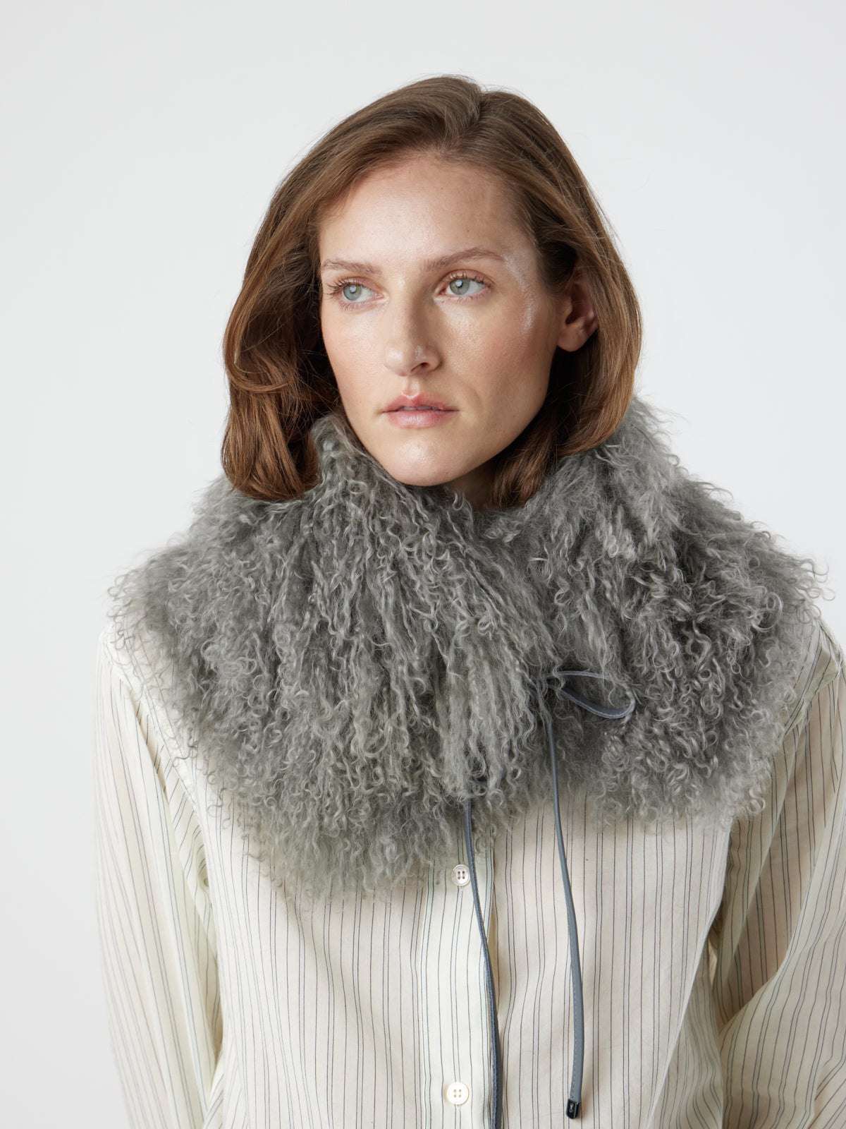 Woman wearing grey Mongolian Shearling Collar Scarf over stripe shirt by gushlow & cole
