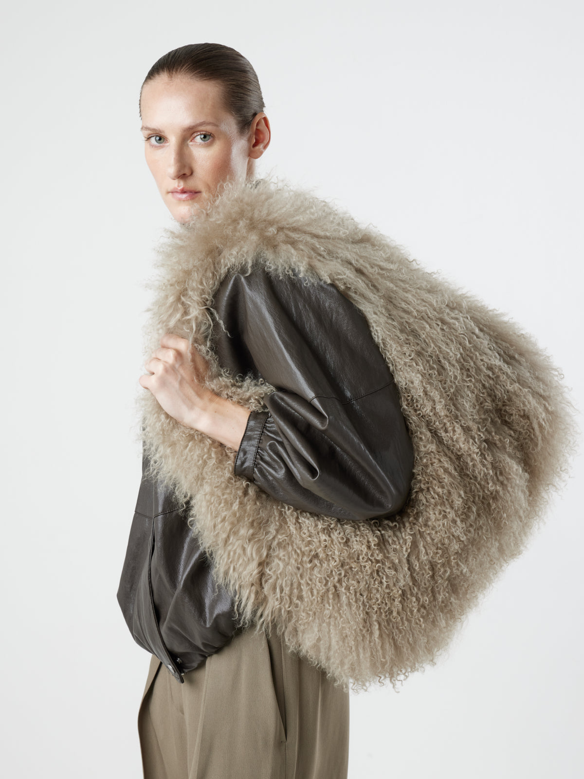 Woman wearing Large Beige Mongolian Shearling Shoulder Bag over shoulder by gushlow & cole on white background