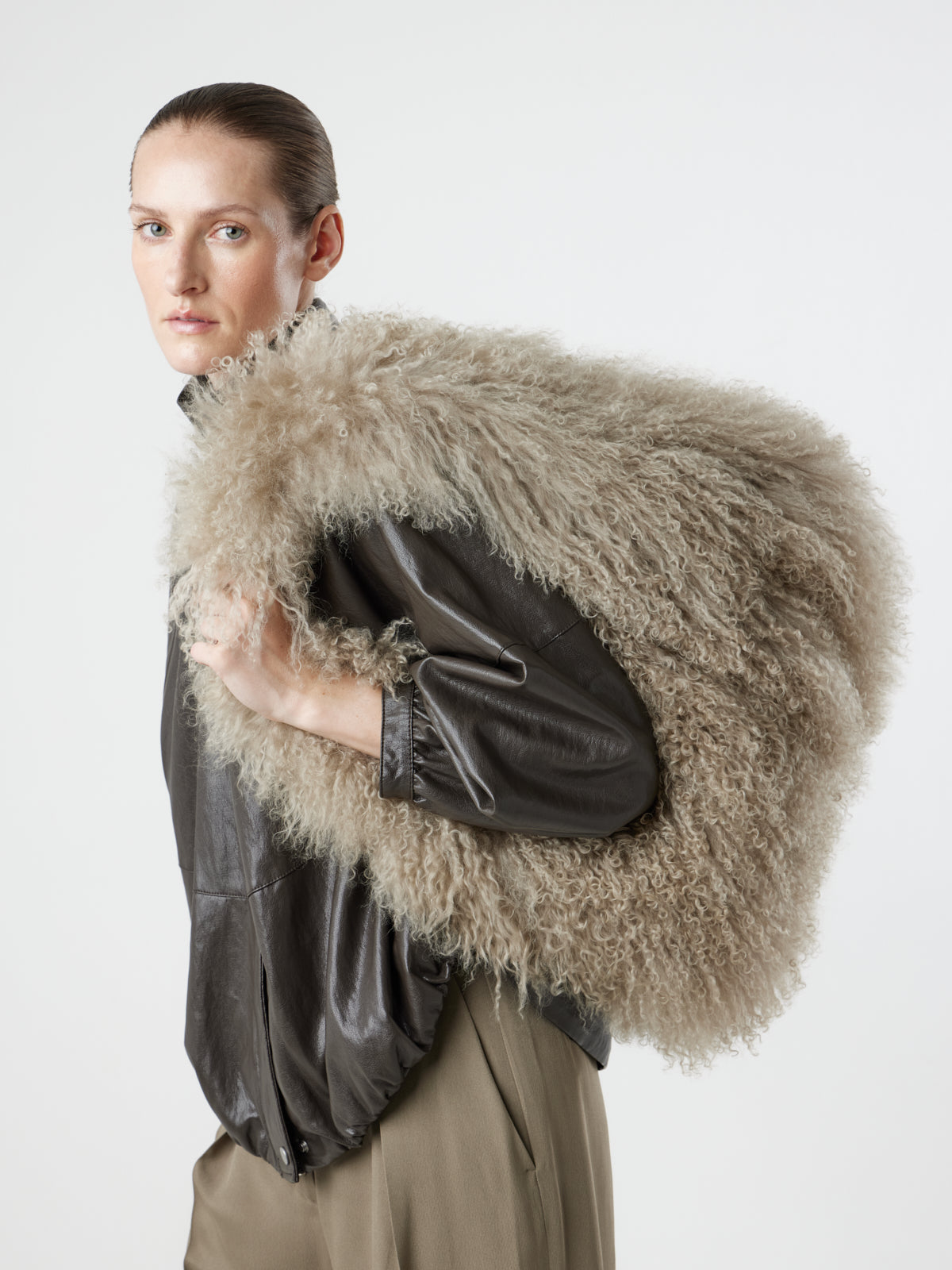 Woman wearing Large Beige Mongolian Shearling Shoulder Bag over shoulder by gushlow & cole on white background