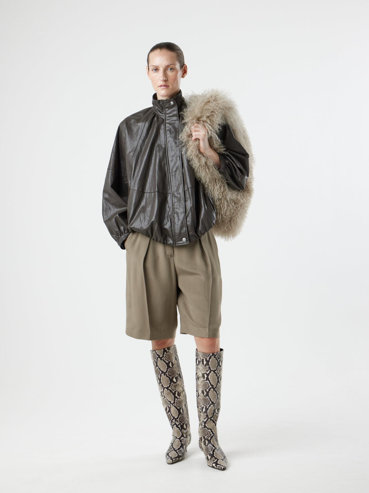 Woman wearing Large Beige Mongolian Shearling Shoulder Bag over left shoulder by gushlow & cole on white background