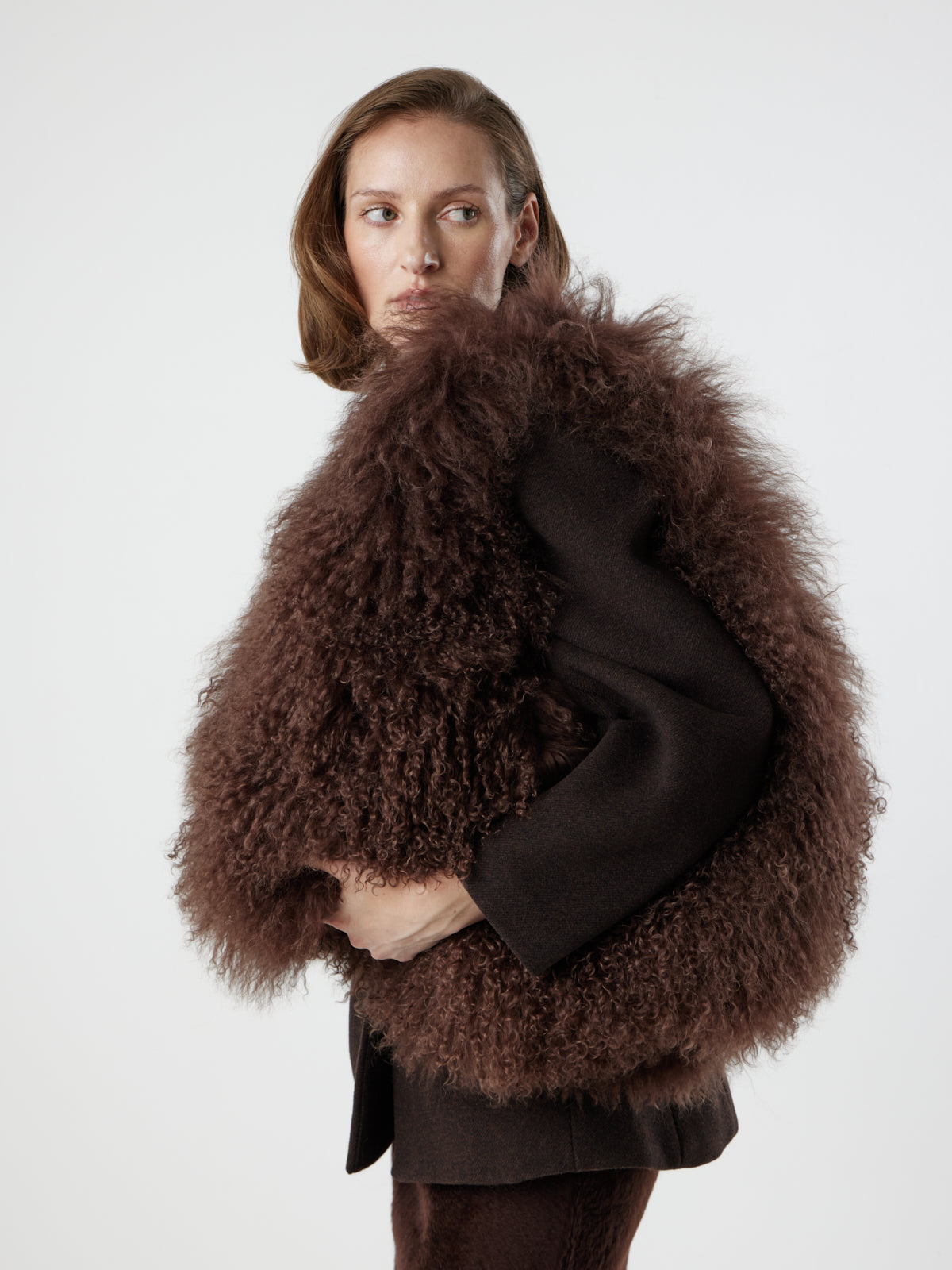Woman wearing Large Brown Mongolian Shearling Shoulder Bag over shoulder by gushlow & cole on white background