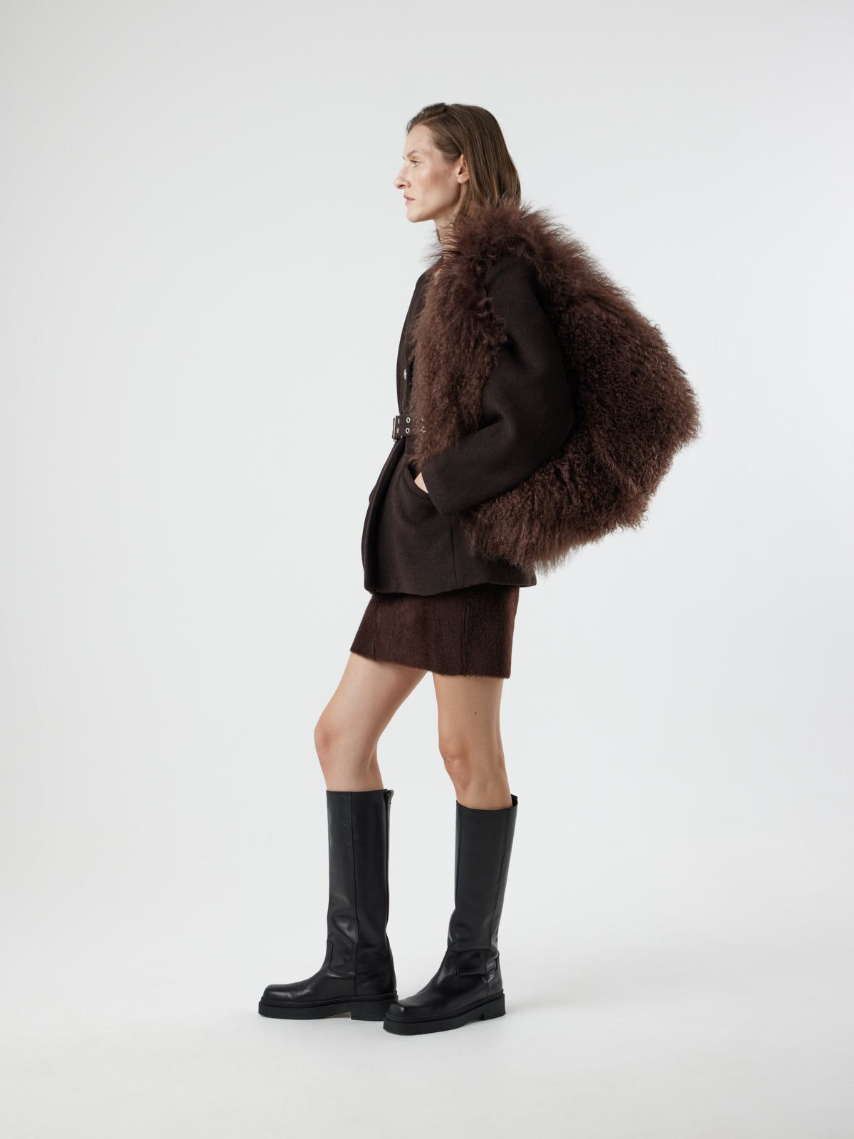 Woman wearing Large Brown Mongolian Shearling Shoulder Bag over shoulder with hand in pocket by gushlow & cole on white background