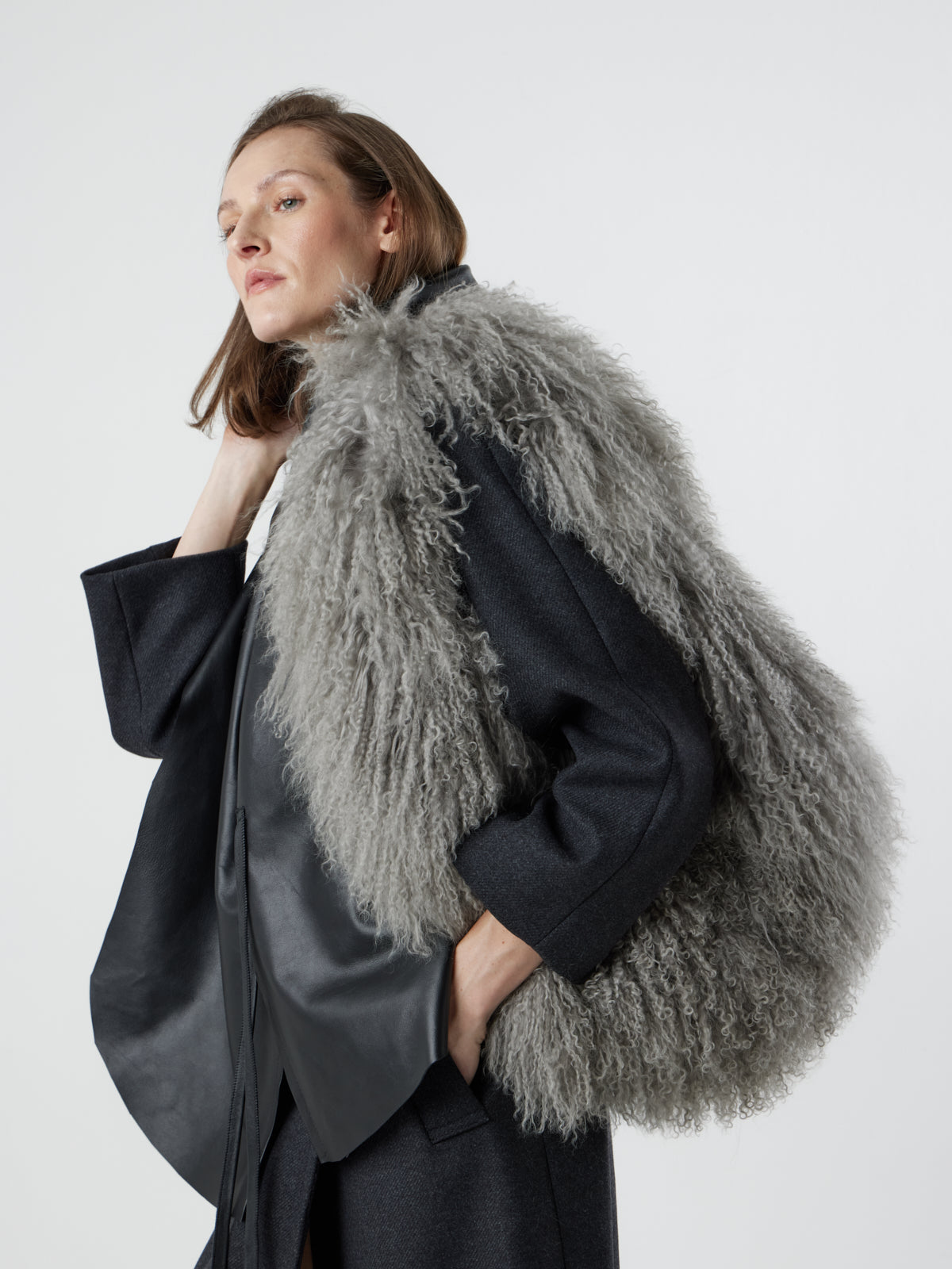 Woman wearing Large Grey Mongolian Shearling Shoulder Bag over shoulder and black leather Shawl Scarf by gushlow & cole on white background