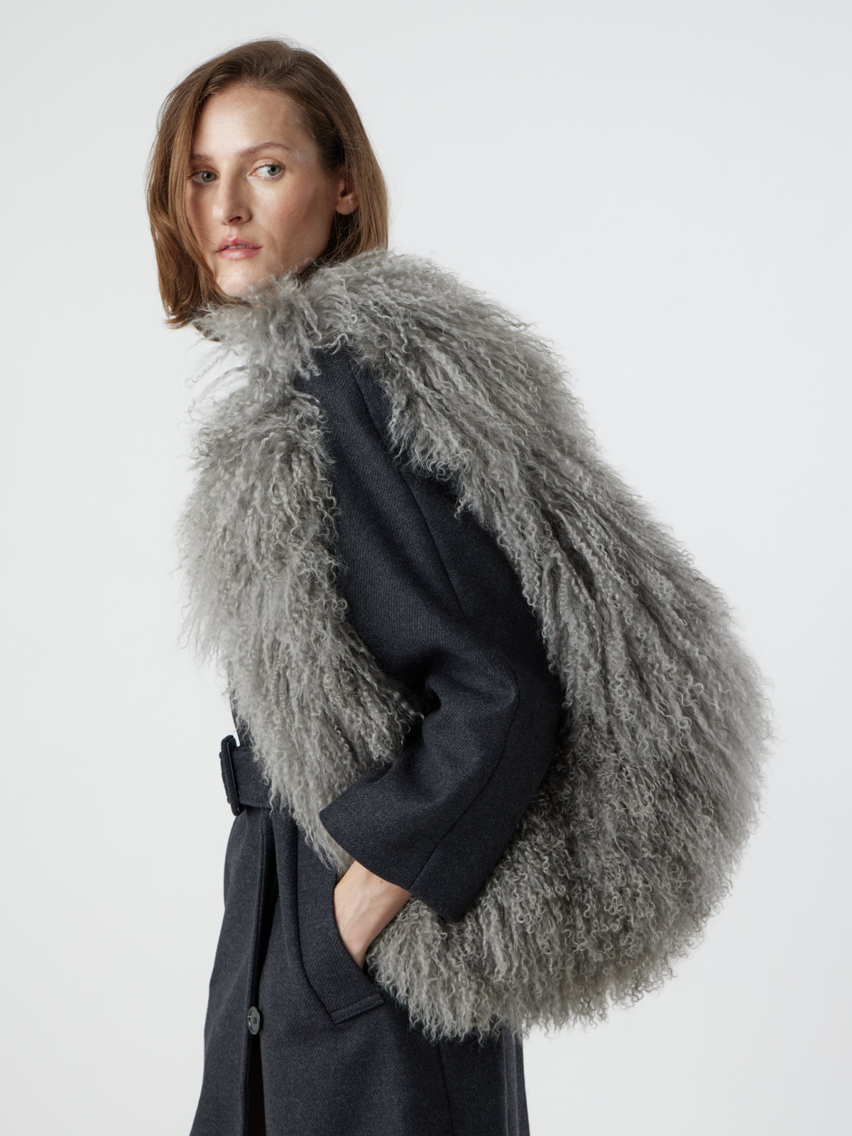 Woman wearing Large Grey Mongolian Shearling Shoulder Bag over shoulder by gushlow & cole on white background