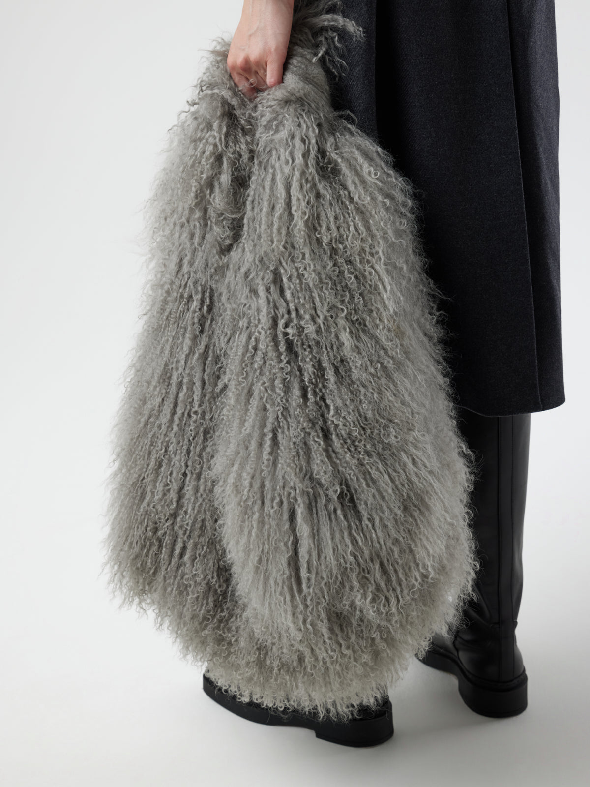 Woman holding Large Grey Mongolian Shearling Shoulder Bag down by side by gushlow & cole on white background