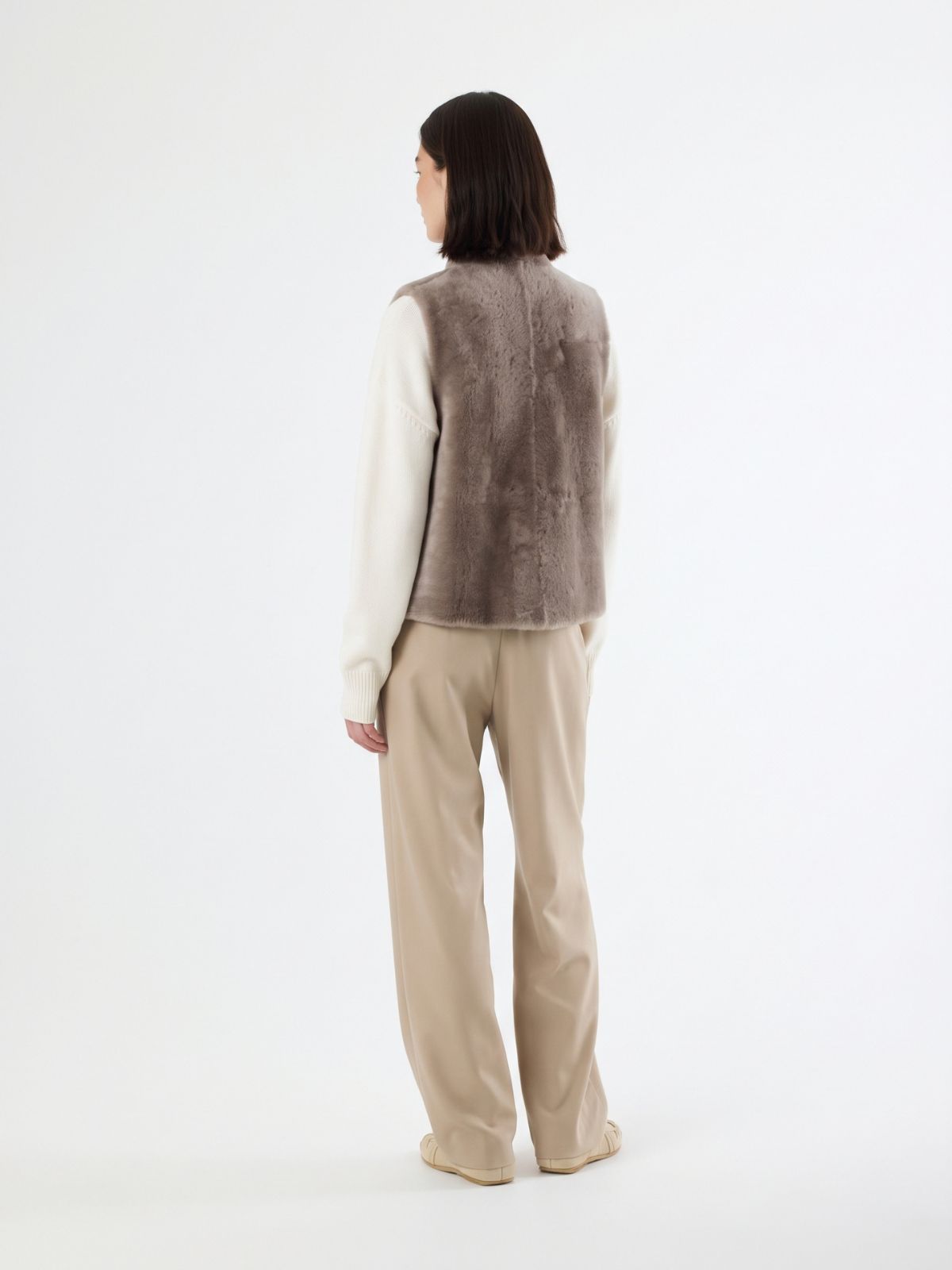 back view of woman wearing natural edge taupe shearling gilet by gushlow & cole