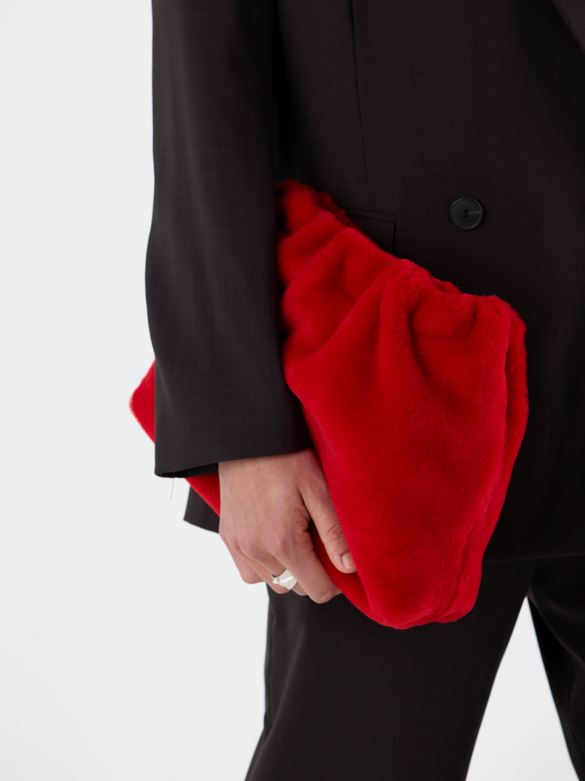 close up of woman holding Red Merino Soft Shearling Clutch by Gushlow & Cole over brown suit