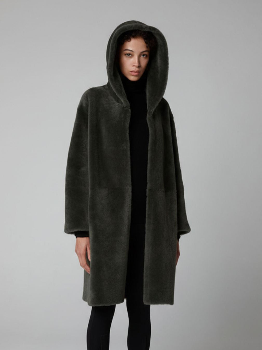 women wearing Storm Green Hooded Shearling Coat by Gushlow & Cole on grey background with hood up