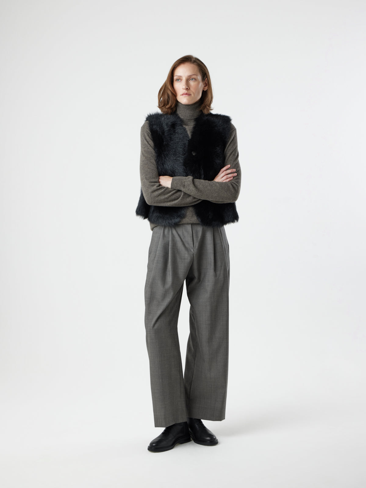 woman wearing Two Button Black Shearling Vest by gushlow & cole with hands in pockets, on white background, with arms crossed