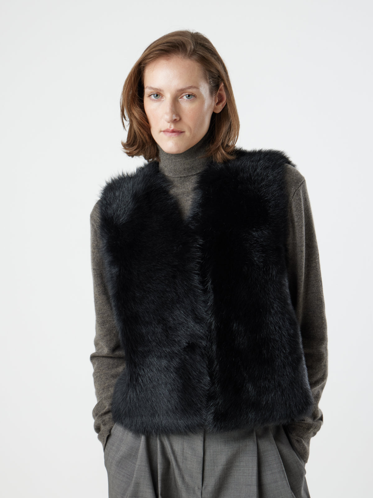 woman wearing Two Button Black Shearling Vest by gushlow & cole with hands in pockets, on white background 