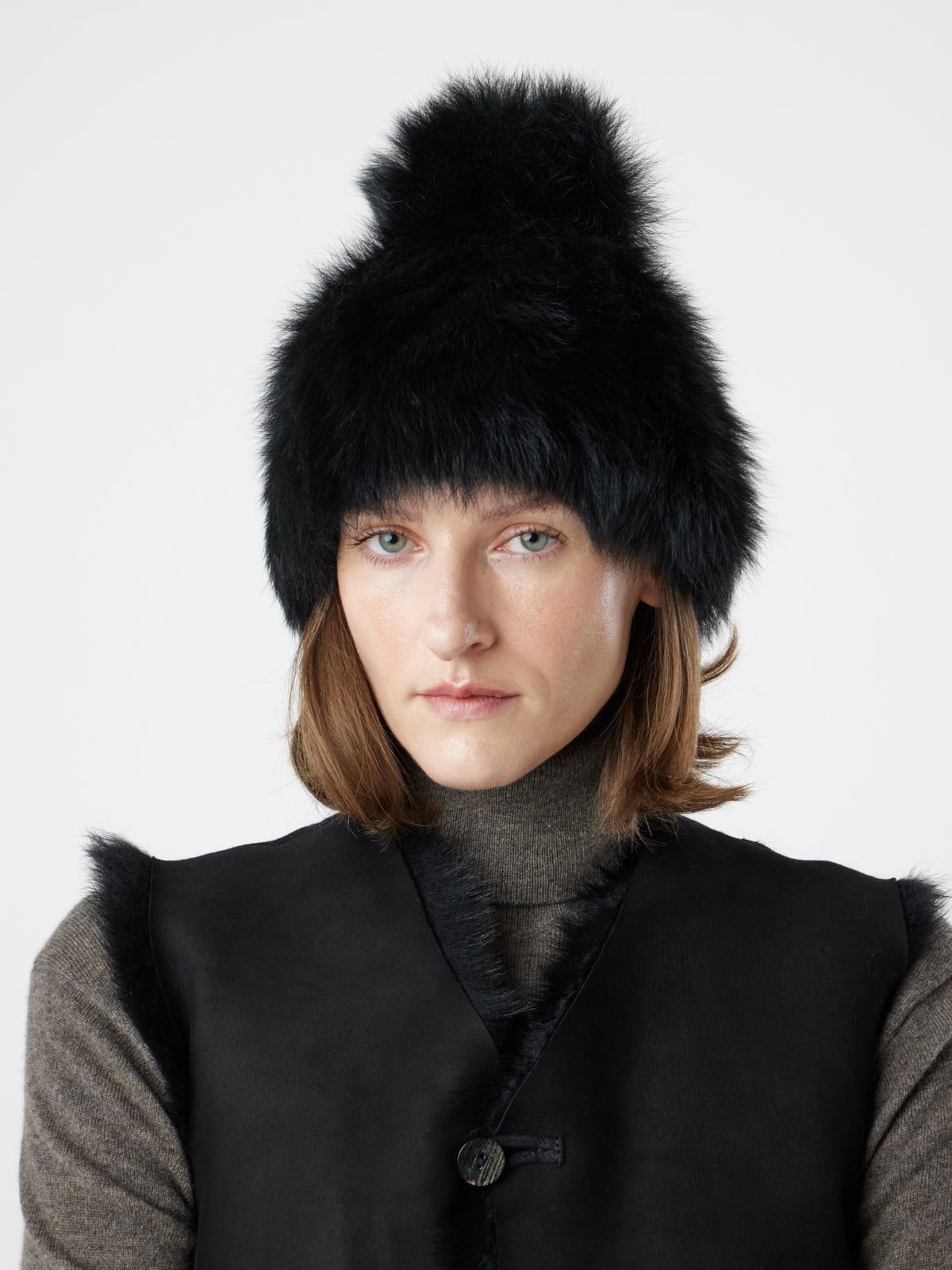 woman wearing Two Button Black Shearling Vest and black toscana shearling beanie hat by gushlow & cole on white background 