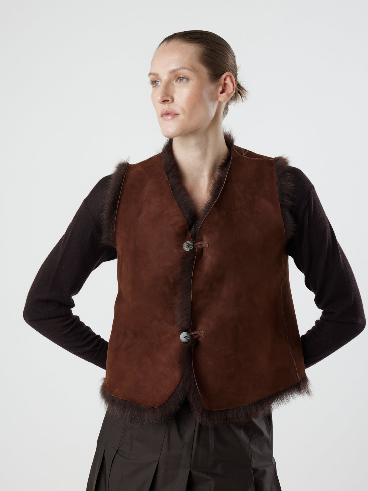 woman wearing reversed Two Button Brown Shearling Vest by Gushlow & Cole over brown jumper on white background