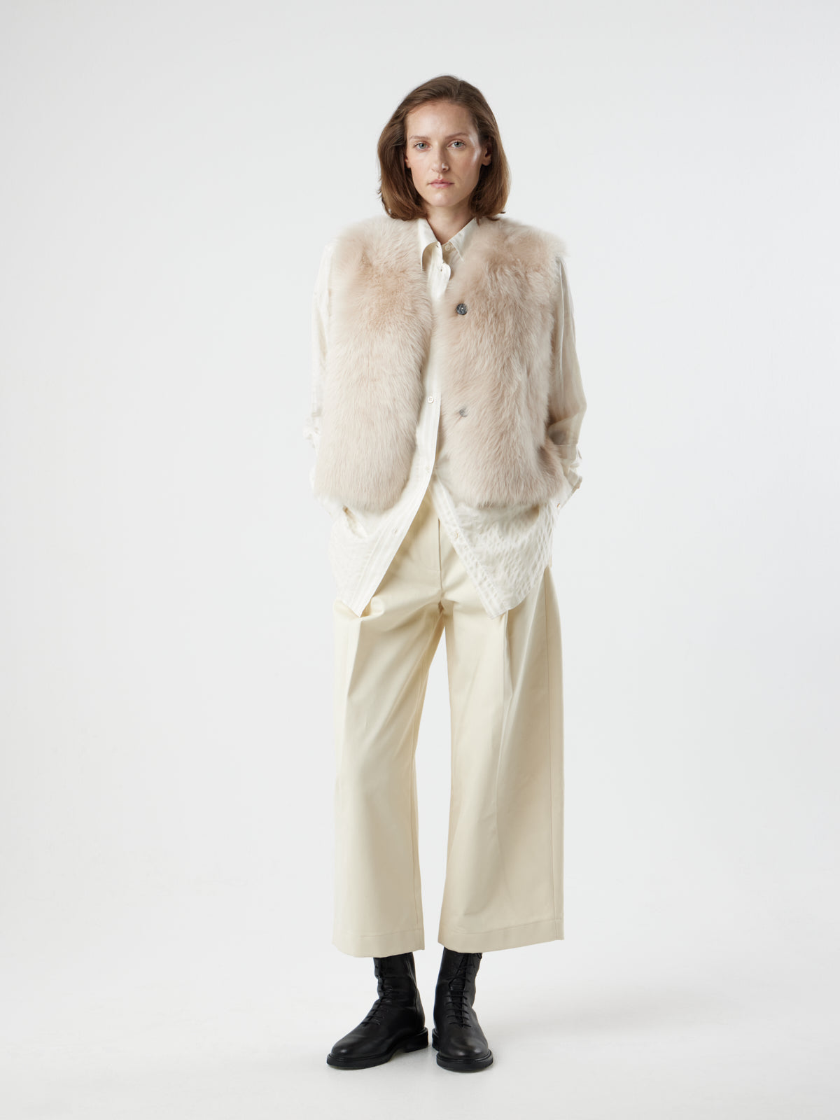 woman wearing Two Button Cream Shearling Vest by gushlow & cole with hands in pockets, on white background 