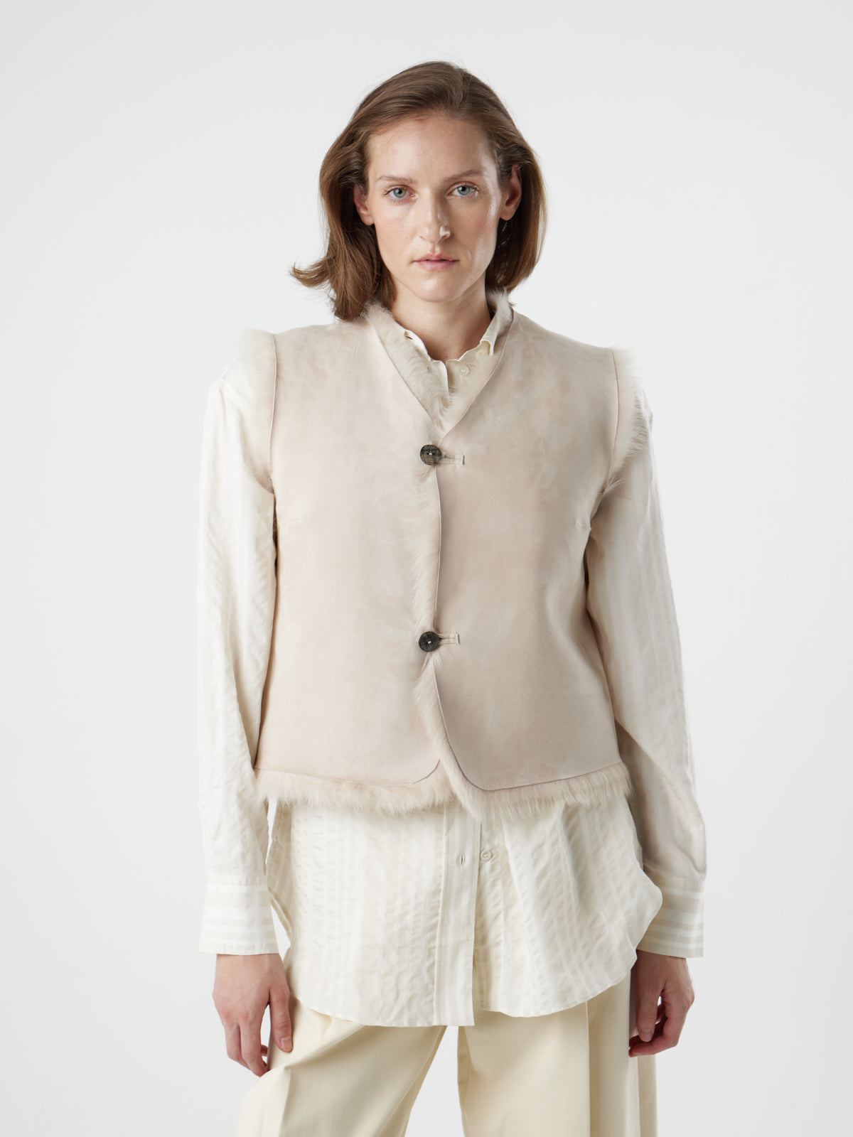 woman wearing reversed, buttoned up Two Button Cream Shearling Vest by gushlow & cole on white background