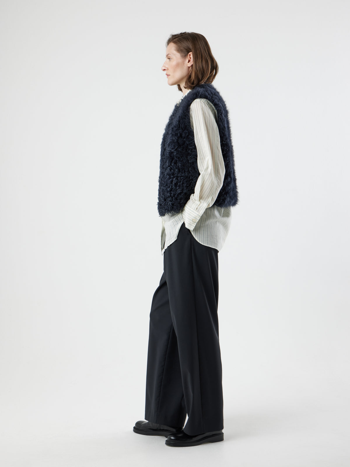 side view of woman wearing two button navy shearling vest by gushlow & cole