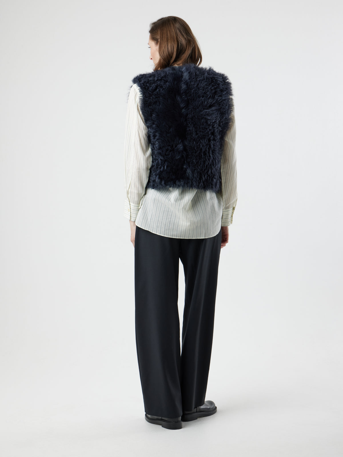 back view of woman wearing two button navy shearling vest by gushlow & cole