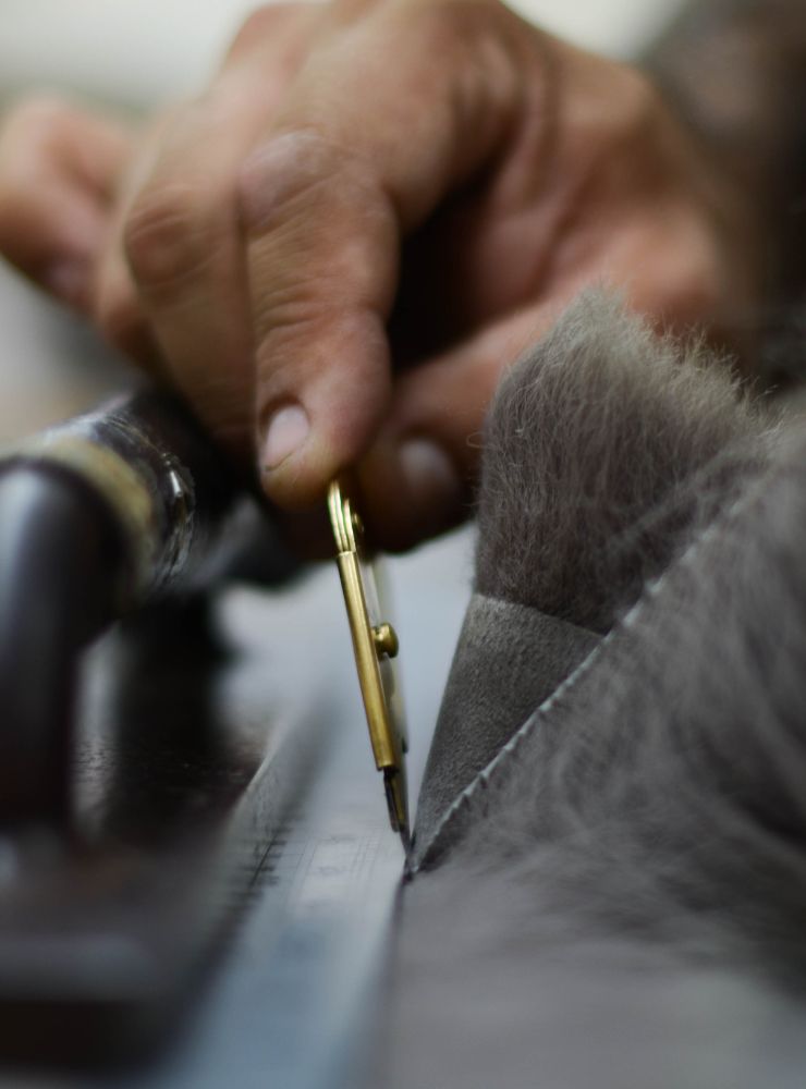 hand holding fur knife cutting toscana shearling - luxury womens shearling gushlow & cole -  lifetime repairs and aftercare