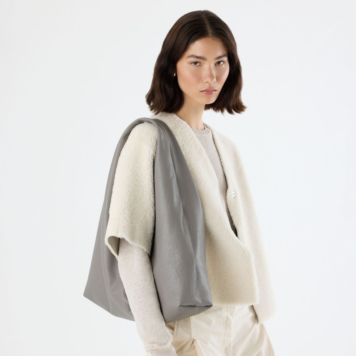 woman wearing grey shearling cardigan and large leather shoulder bag on white background - luxury womens shearling gushlow & cole