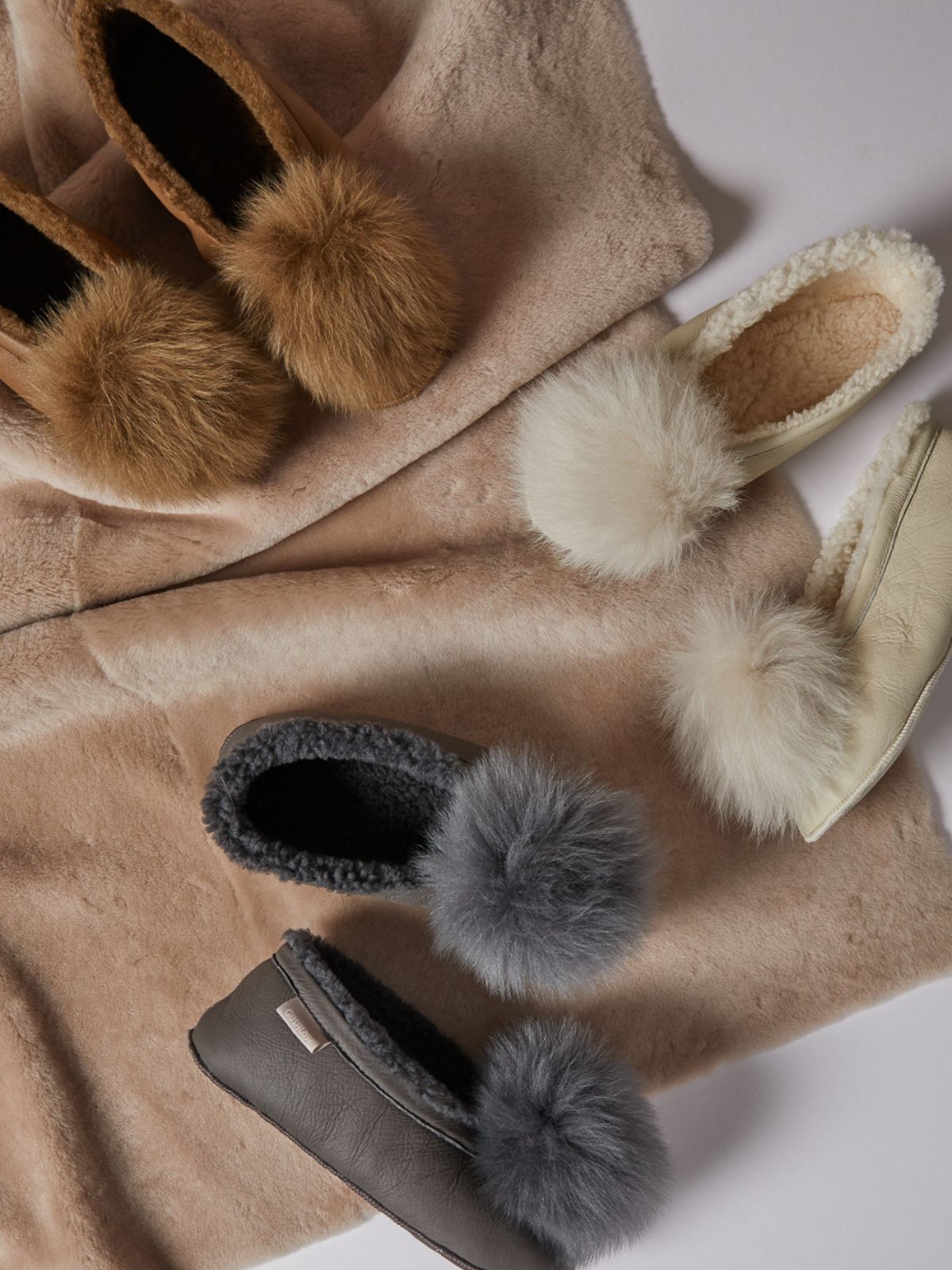 shearling slippers in cream, grey and tan on shearling throw by gushlow & cole